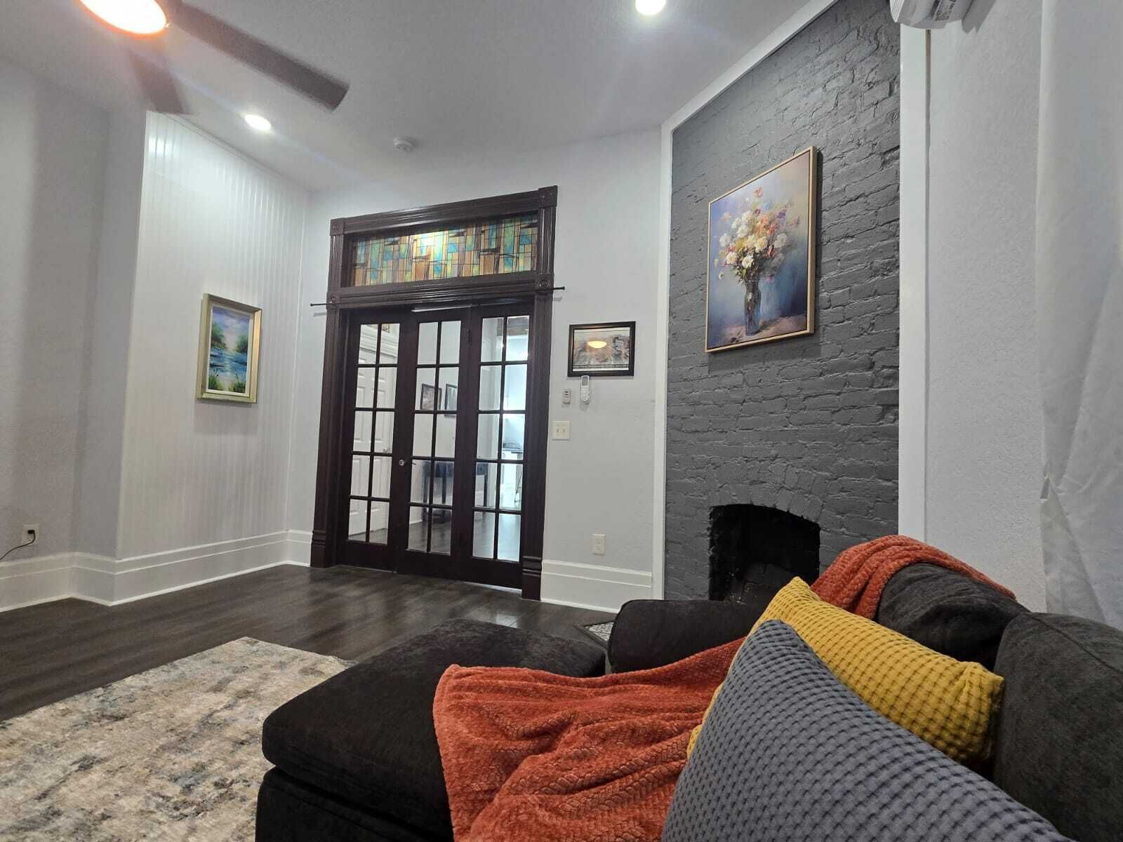 A living room with a dark wood door, a fireplace, and a gray brick accent wall.