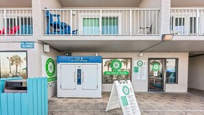 Un edificio con una máquina expendedora que dice 'ICE 24 hora vending' y un letrero que anuncia 'SUMMER MARKET'.