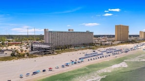 A beachfront hotel with multiple floors, a sandy beach in front, and several umbrellas and lounge chairs. - Summit Unit 422 Gulf Front 1 Bedroom/Bunks (Panama City Beach)