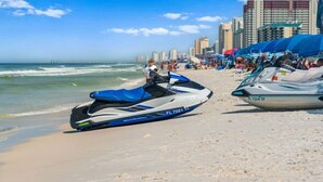 Un jet ski en la playa con un horizonte urbano al fondo.