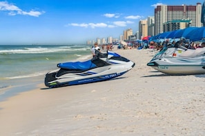 Ein Jetski am Strand, im Hintergrund die Skyline einer Stadt.
