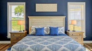A bedroom with a bed, two nightstands, a headboard, and two windows with blinds. - Lakefront Escape | Private Pool + Dock Access (Mineral)