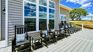 A deck with multiple chairs and tables, a large window, and a tree in the background. - Lakefront Escape | Private Pool + Dock Access (Mineral)
