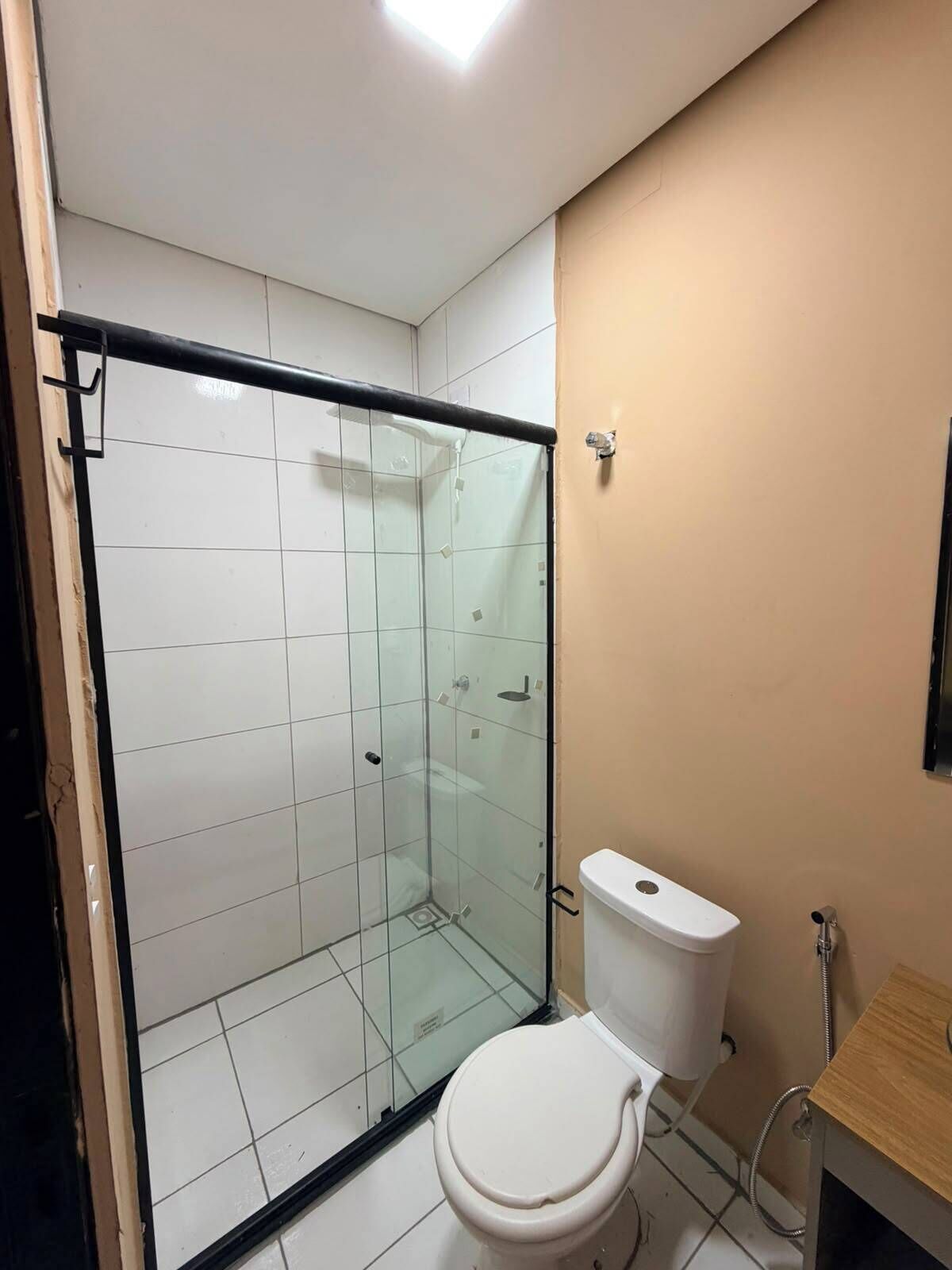 A bathroom with a glass-enclosed shower, a white toilet, and a wooden vanity.