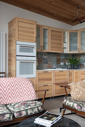 Eine moderne Küche mit Holzschränken, einem eingebauten Backofen und einer gefliesten Spritzschutzwand.