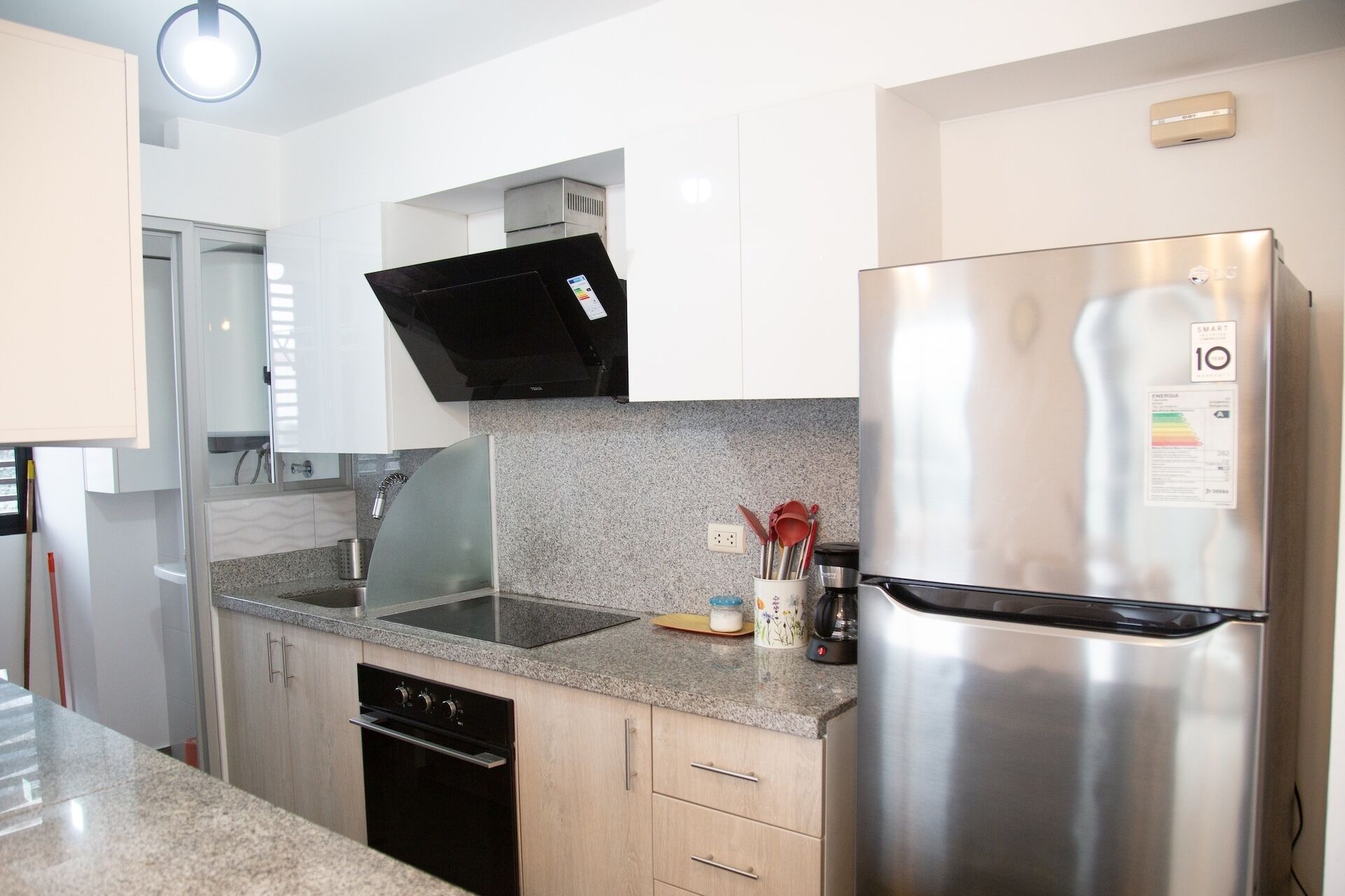 A modern kitchen with stainless steel appliances, granite countertops, and white cabinetry.