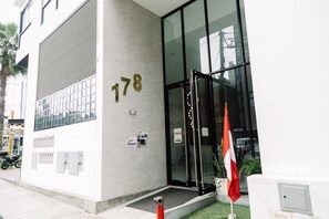 A building with a large glass entrance, the number 178 on the wall, and a flag outside. - Newly Renovated 2BR Apartment (Lince)