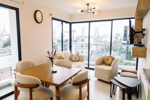 A modern living room with a dining area, large windows, and a city view. - Newly Renovated 2BR Apartment (Lince)