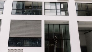 A modern multi-story building with a flat facade, large windows, and a ground-level entrance with a glass door. - Newly Renovated 2BR Apartment (Lince)