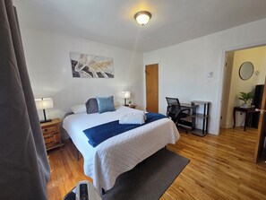 Ein Hotelzimmer mit Bett, Nachttischlampen, Schreibtisch und Stuhl.