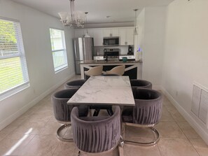 A modern kitchen with white cabinets, a stainless steel refrigerator, and a microwave. - Charming 3-bedroom house with AC in Sunny Cape Coral (Cape Coral)