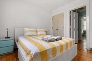 Ein Schlafzimmer mit einem Bett, einem Nachttisch und einer Tür zu einem anderen Raum.