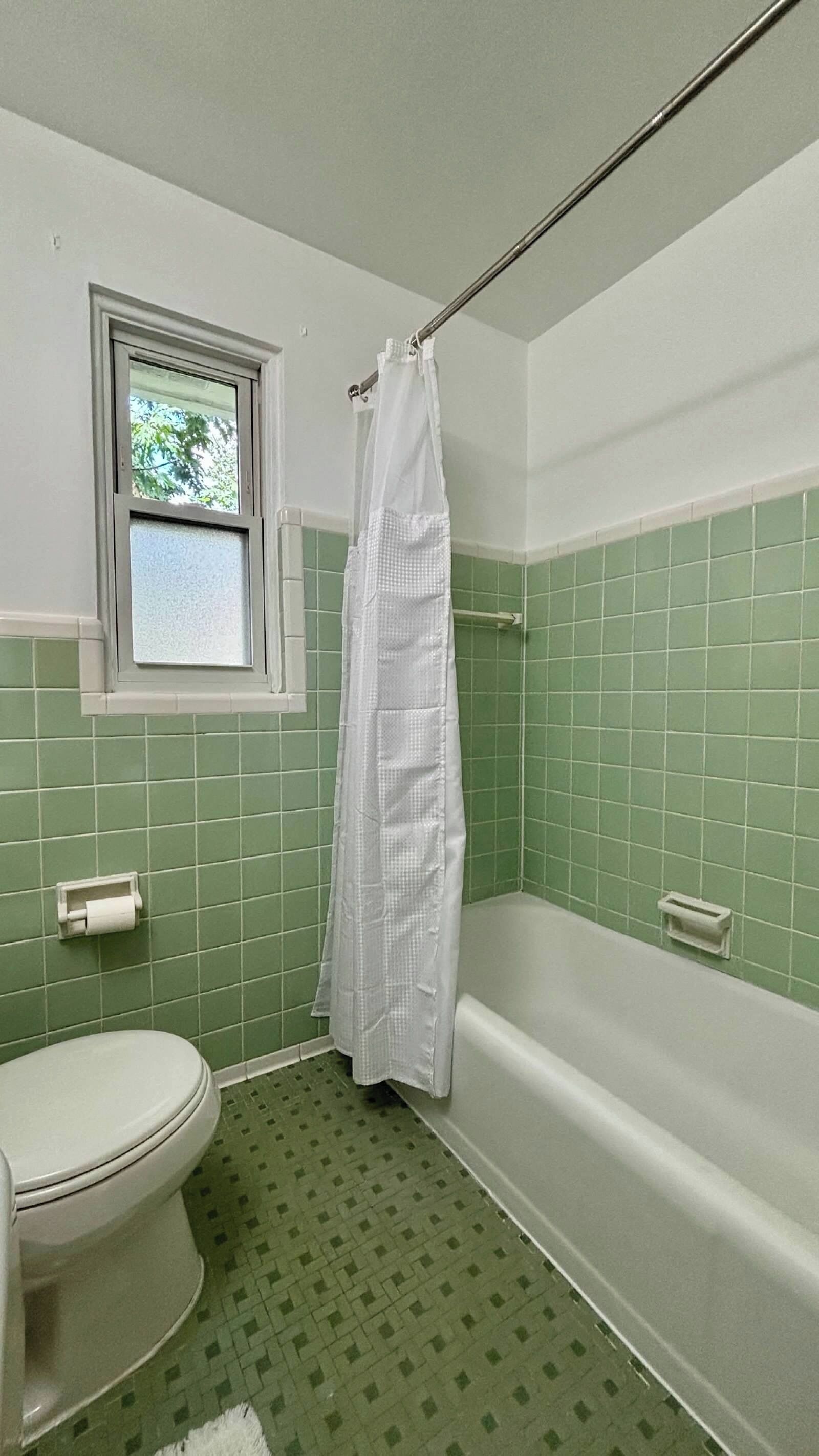 Un baño con inodoro, bañera y cortina de ducha.