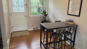 Un coin repas avec une table et des chaises, une plante en pot et une carte encadrée accrochée au mur.
