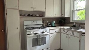 Une cuisine avec des meubles blancs, une cuisinière et un évier.