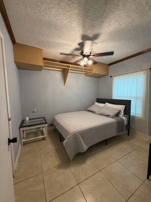 A bedroom with a bed, a nightstand, a ceiling fan, and a window with blinds. - Spacious 4BR Houston Family Home- Pet Friendly (Houston)