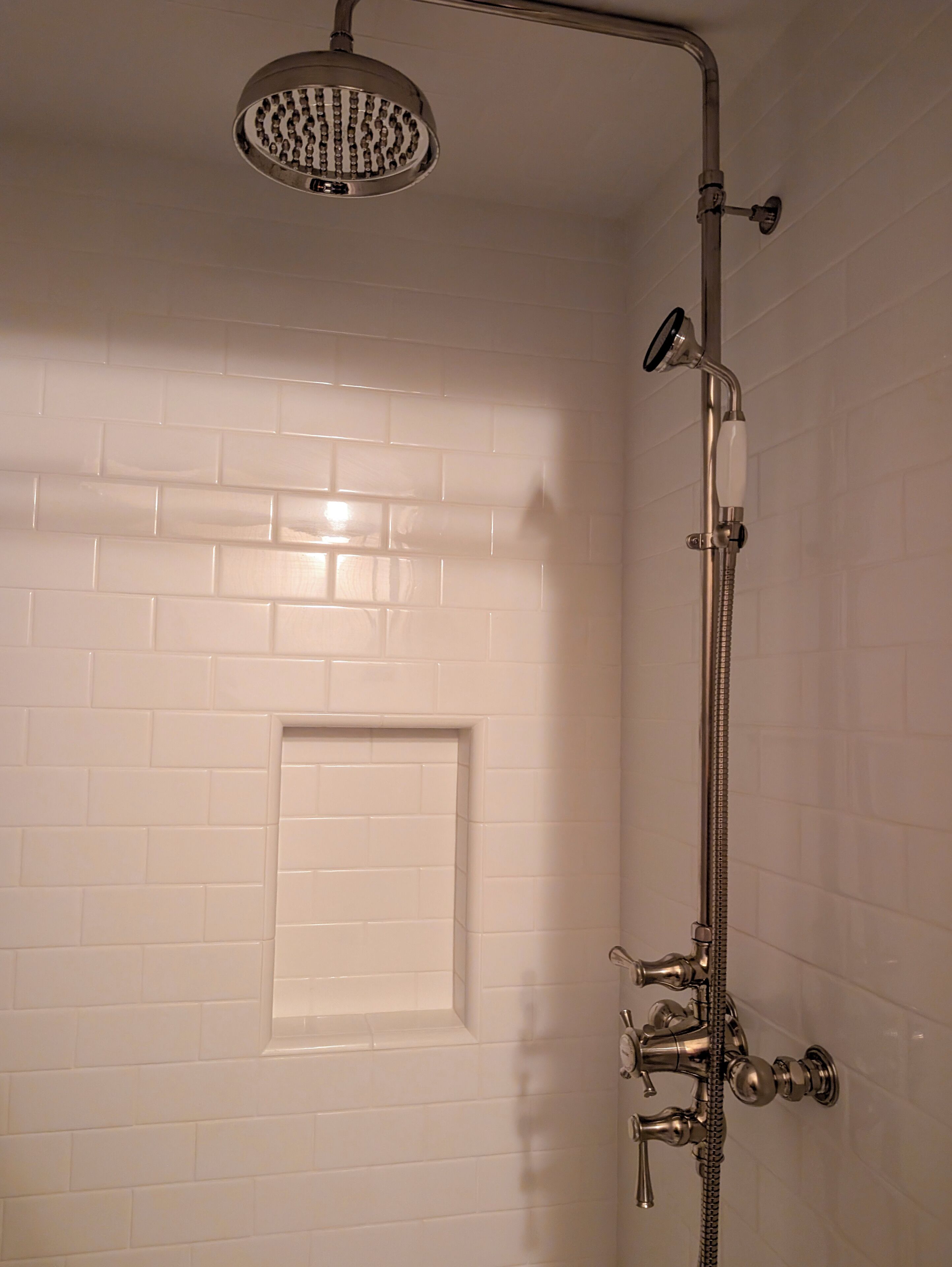 Eine Dusche mit Handbrause und Armaturen an der Wand.
