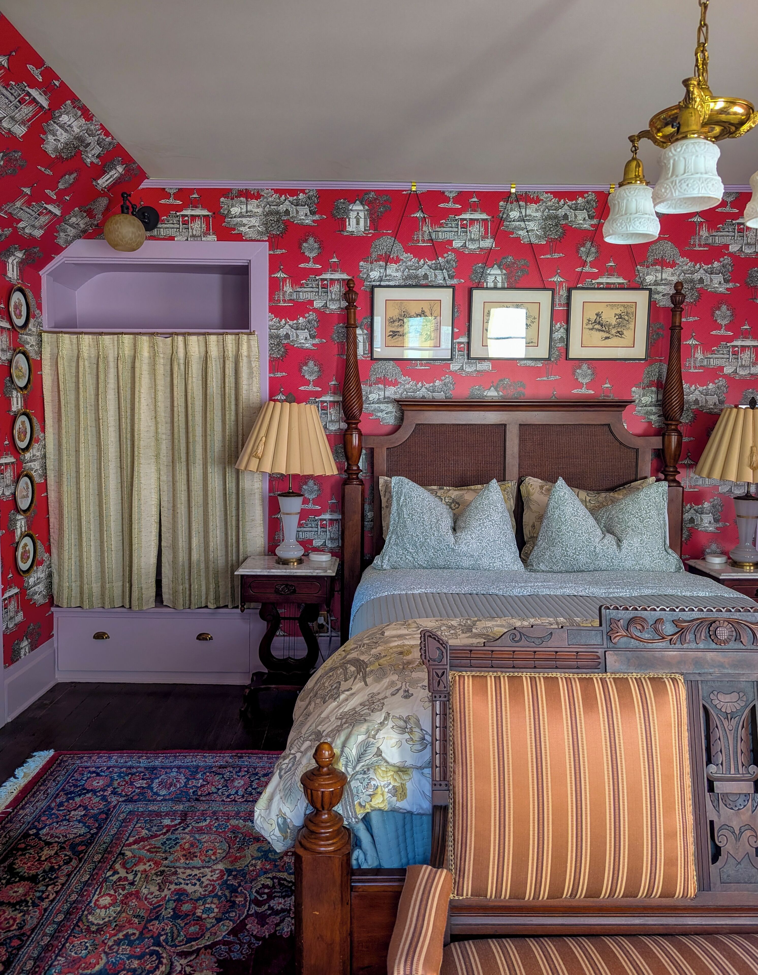 Un dormitorio con cama, cómoda, mesita de noche, lámpara, espejo y pared decorada.