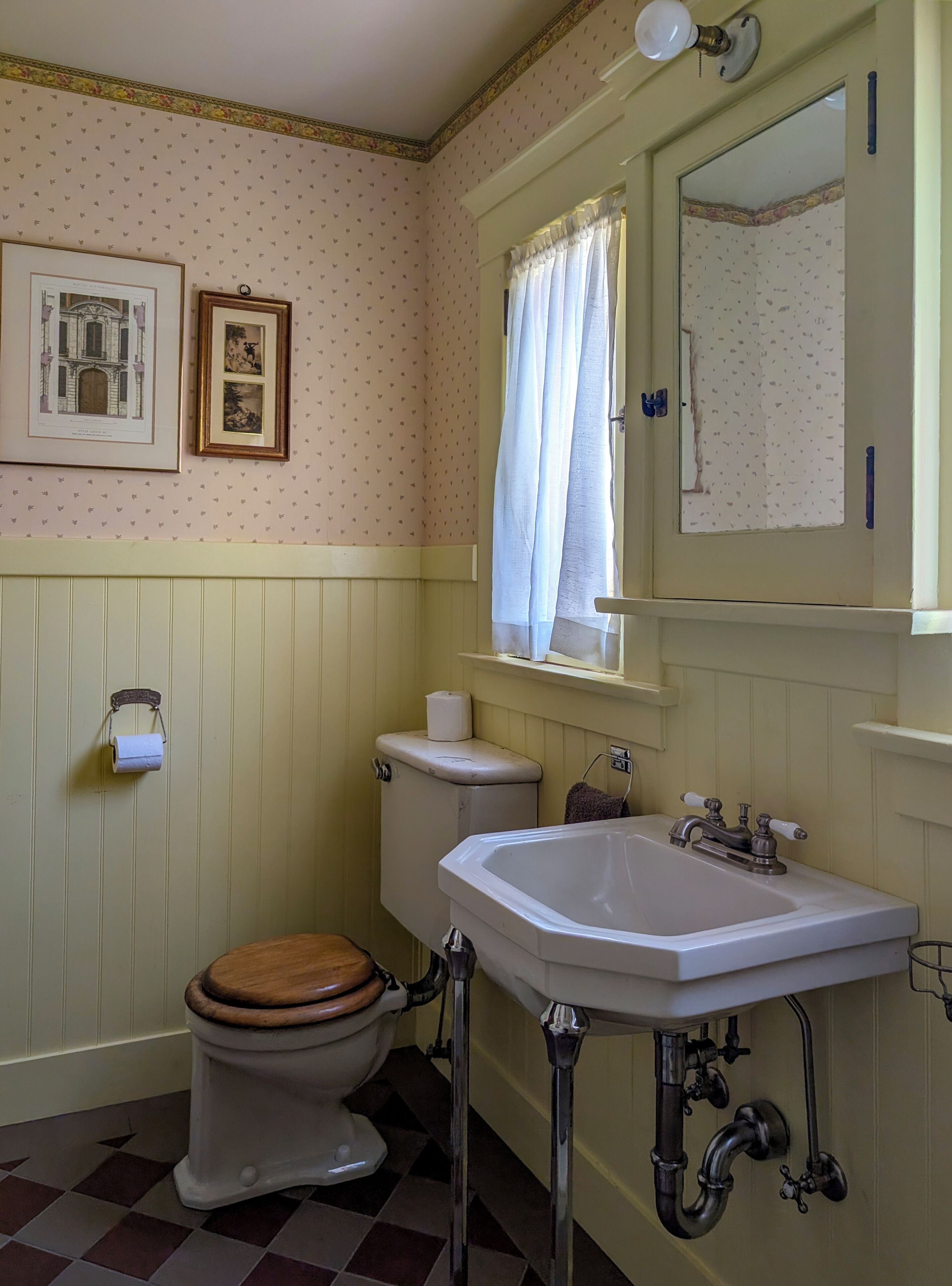 A bathroom with a toilet, sink, and a mirror above the sink.