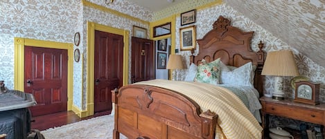 A bedroom with a wooden bed, a nightstand with a lamp, a dresser, and a door with a decorative handle.