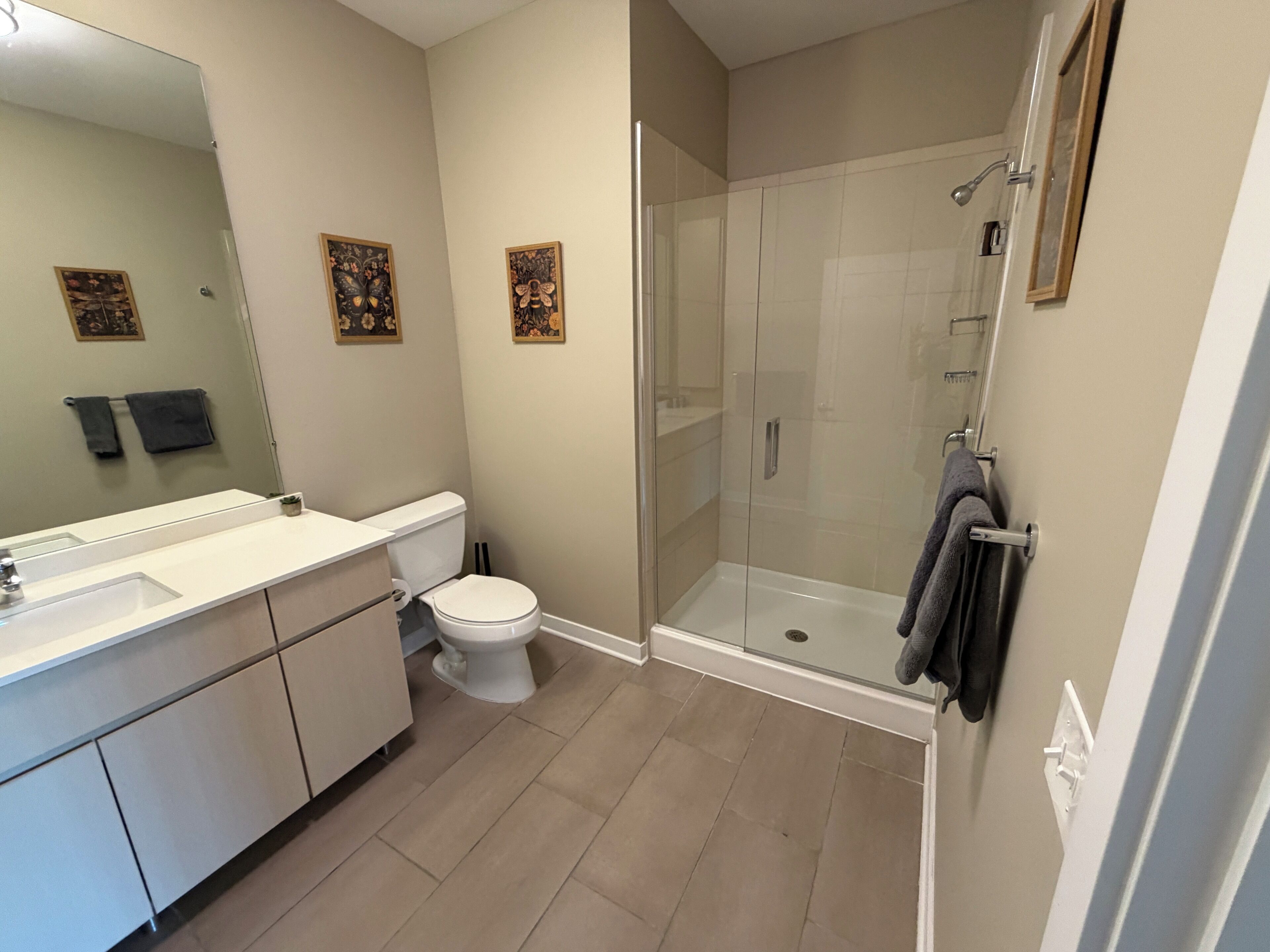 Un baño moderno con ducha acristalada, lavamanos blanco y retrete.