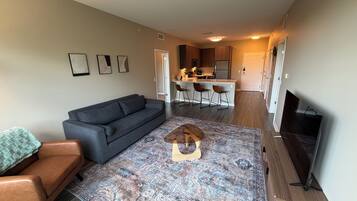 A living room with a sofa, a coffee table, a TV, and a patterned rug.