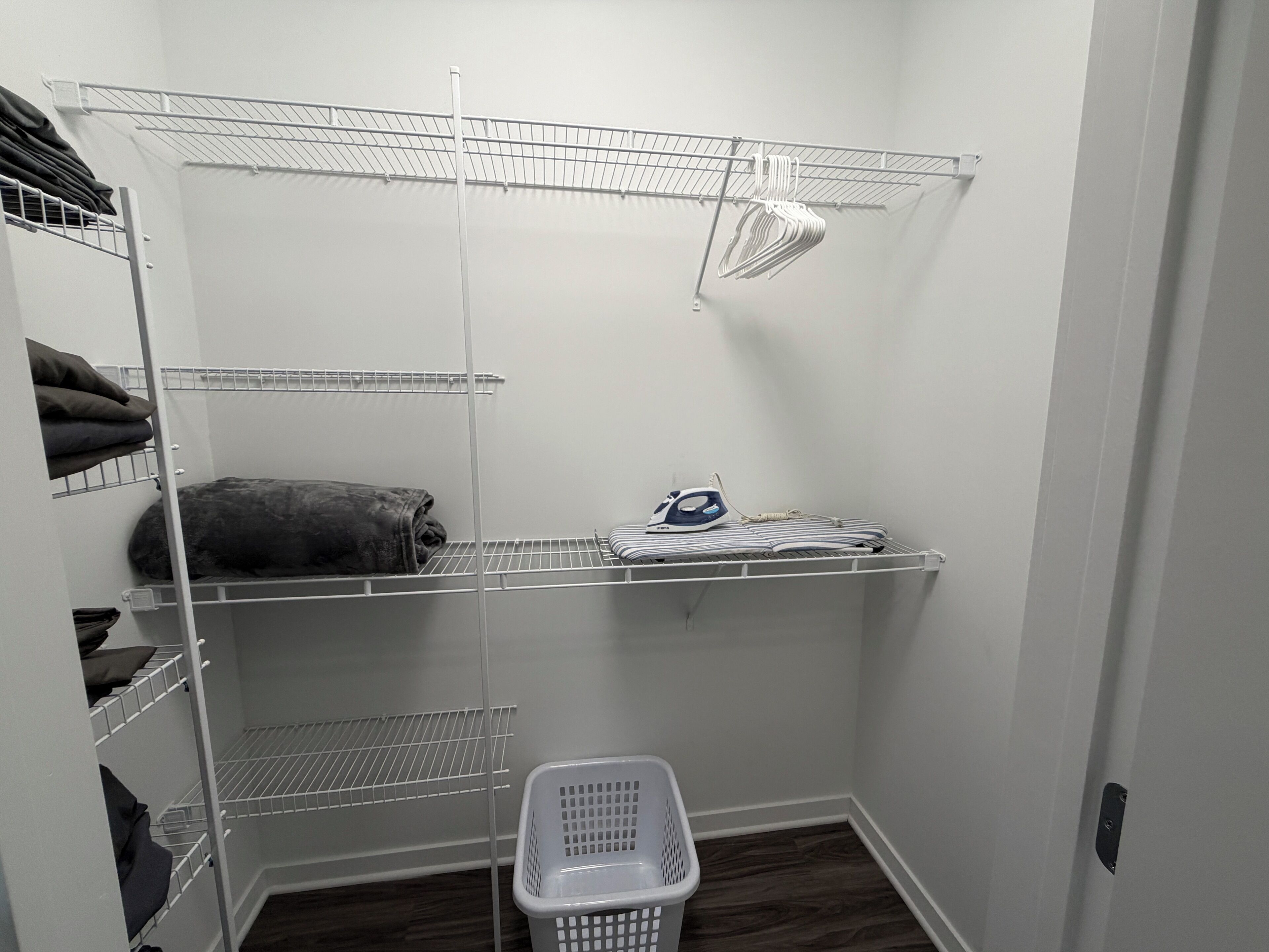 A laundry room with metal shelving, a laundry basket, and an iron.