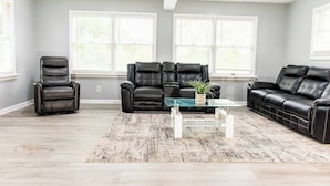 A living room with a black leather sofa, a recliner, and a coffee table with a plant.