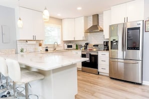 A modern kitchen with white cabinetry, stainless steel appliances, and a central island.