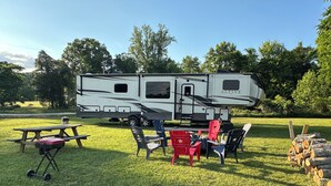 A recreational vehicle with a picnic table and chairs in a grassy area. - Glamping in Rock Island (Walling)