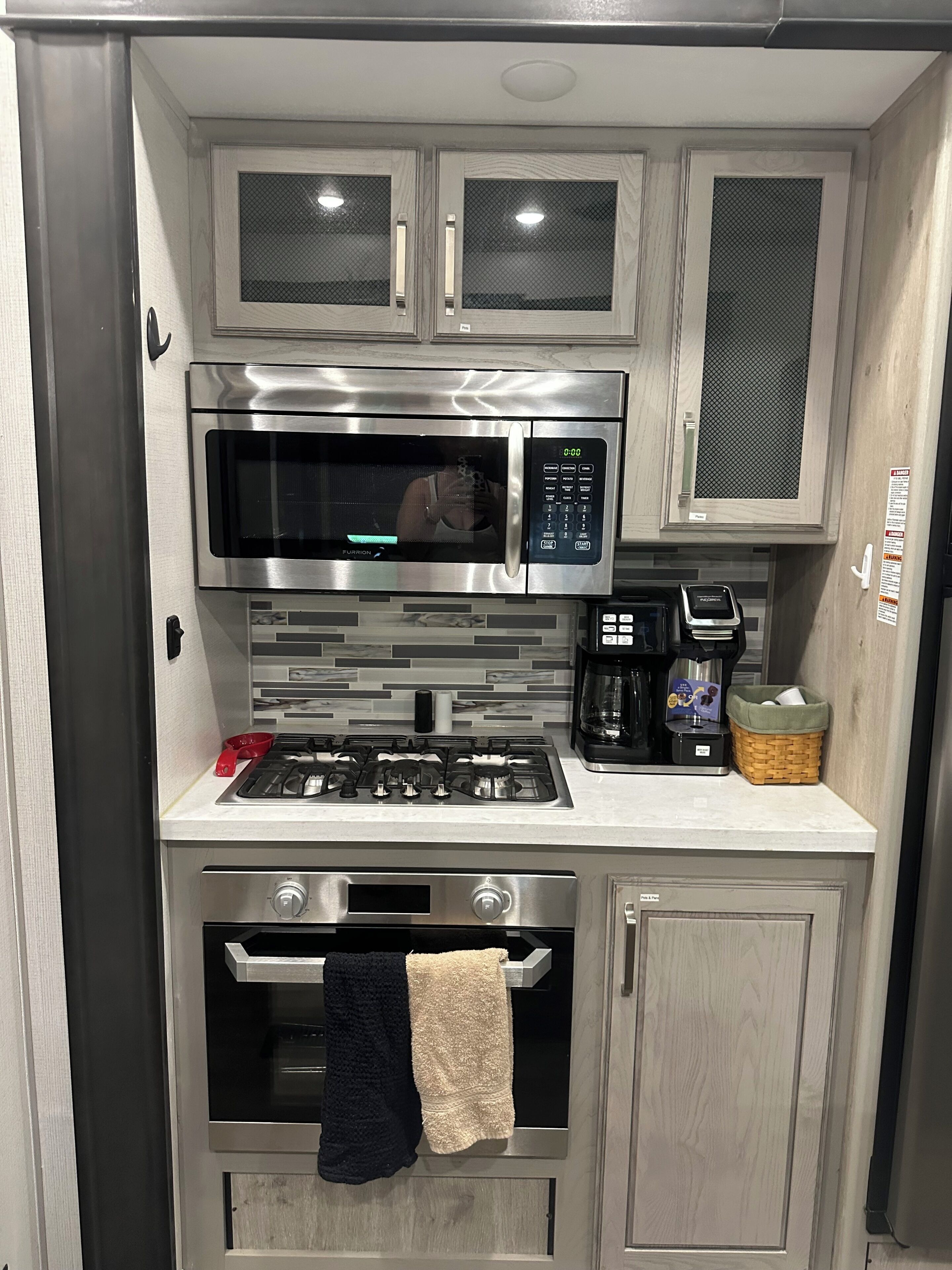 Cocina compacta con microondas de acero inoxidable, estufa y horno a gas.
