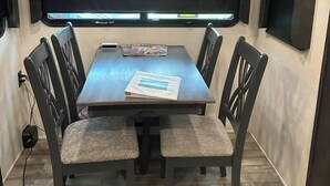 A conference room with a large table, four chairs, a projector screen, and a ceiling light fixture. - Glamping in Rock Island (Walling)