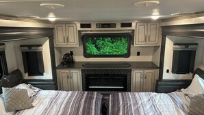 A bedroom with a bed, a television, cabinets, and a fireplace. - Glamping in Rock Island (Walling)