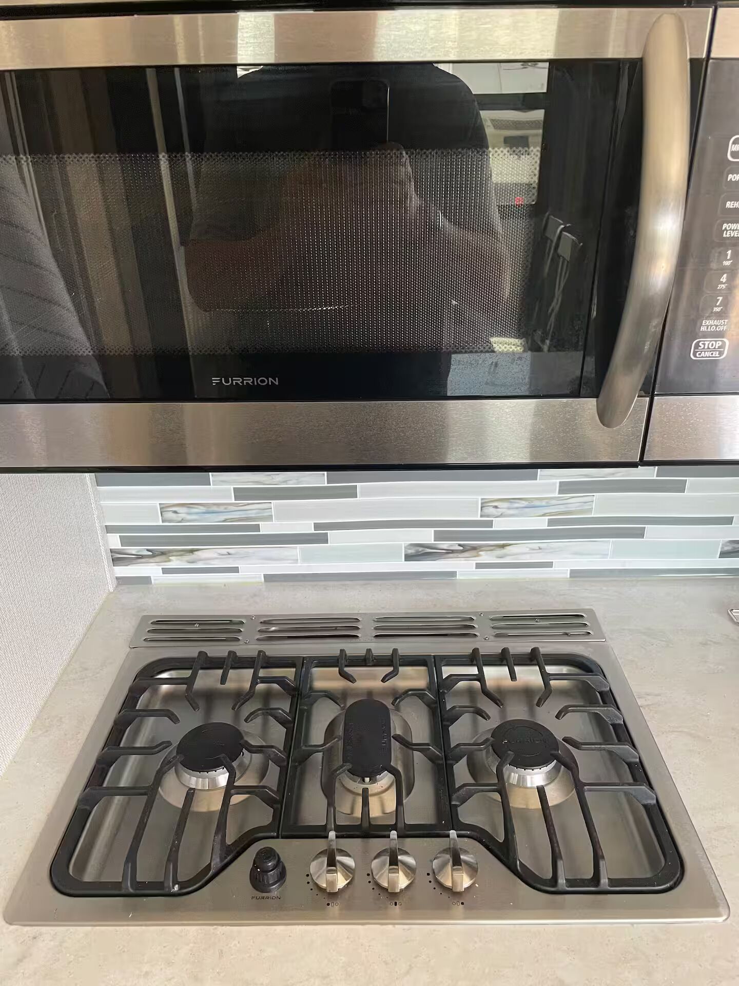 Una cocina con campana de acero inoxidable y estufa a gas con cuatro quemadores.