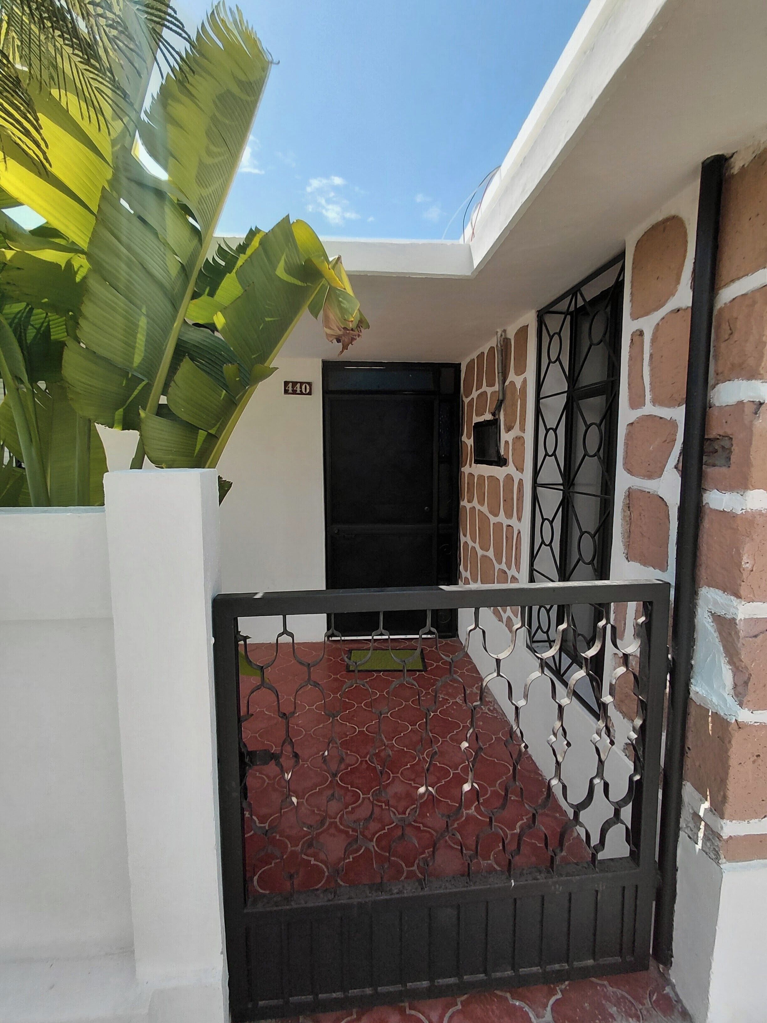 Un bâtiment avec un mur en pierre, une porte noire et un portail en métal.