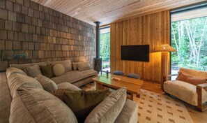 A cozy living room with a wooden wall, a sofa, a coffee table, and a TV.
