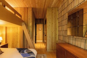 A wooden interior with a bed, bedside table, and a dresser. - New-Cedar House-Your Private Coastal Retreat! (Ucluelet)