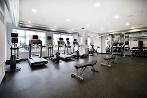 Un gimnasio con cintas de correr, elípticas y equipos de levantamiento de pesas.