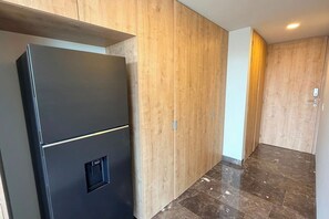 Ein Flur mit Holzwänden, einem schwarzen Kühlschrank und einem Marmorboden.