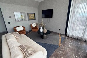 Een moderne woonkamer met een bank, twee fauteuils, een salontafel en kunstwerken aan de wanden.