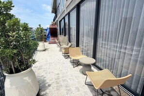 Een terras op het dak met buitenmeubilair, potplanten en uitzicht op de stadsgezicht.