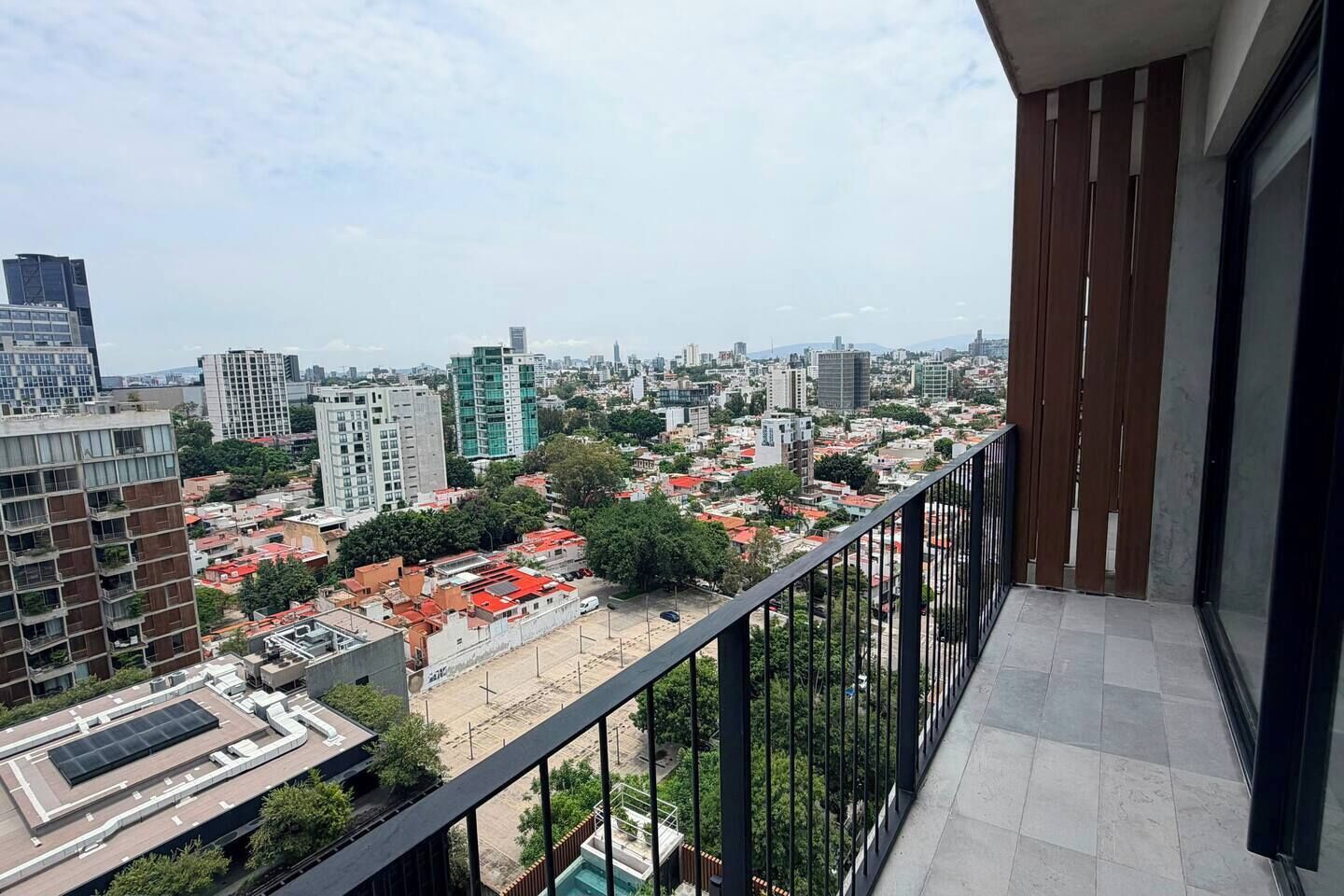 Un balcon avec vue sur la ville, offrant un panorama sur des bâtiments modernes et un ciel dégagé.