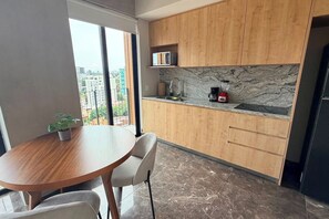 A modern kitchen with wooden cabinets, a marble backsplash, and a dining area with a round table and chairs. - Suite de lujo, Jacuzzi y Alberca | Punto São Paulo (Guadalajara)