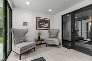 A modern room with two armchairs, a small table with a plant, and a framed picture on the wall.