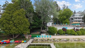 A dock with kayaks, a small building, and a large tree. - Victorian Inn #226 | 2 Queen Beds (Elkhart Lake)