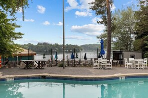 Ein Poolbereich mit Pool, Tischen, Stühlen und Sonnenschirmen.