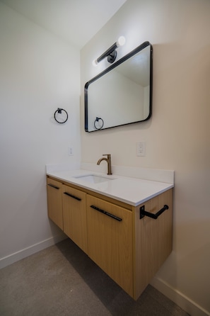 A bathroom with a white sink, wooden cabinets, a mirror, and a towel ring. - Long Beach 3 Bedroom Apartment Near Beach, Dining, CSULB, Long Beach Airport (Long Beach)