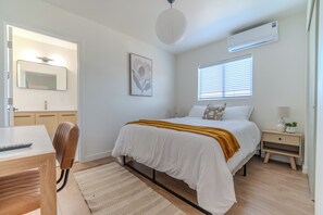A modern bedroom with a bed, bedside table, lamp, and a window with blinds. - Long Beach 3 Bedroom Apartment Near Beach, Dining, CSULB, Long Beach Airport (Long Beach)