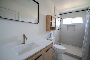 A bathroom with a white sink, a toilet, a shower, and a mirror. - Long Beach 3 Bedroom Apartment Near Beach, Dining, CSULB, Long Beach Airport (Long Beach)