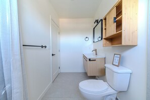 Ein kleines, sauberes Badezimmer mit Toilette, Waschbecken und einem Holzkästen.